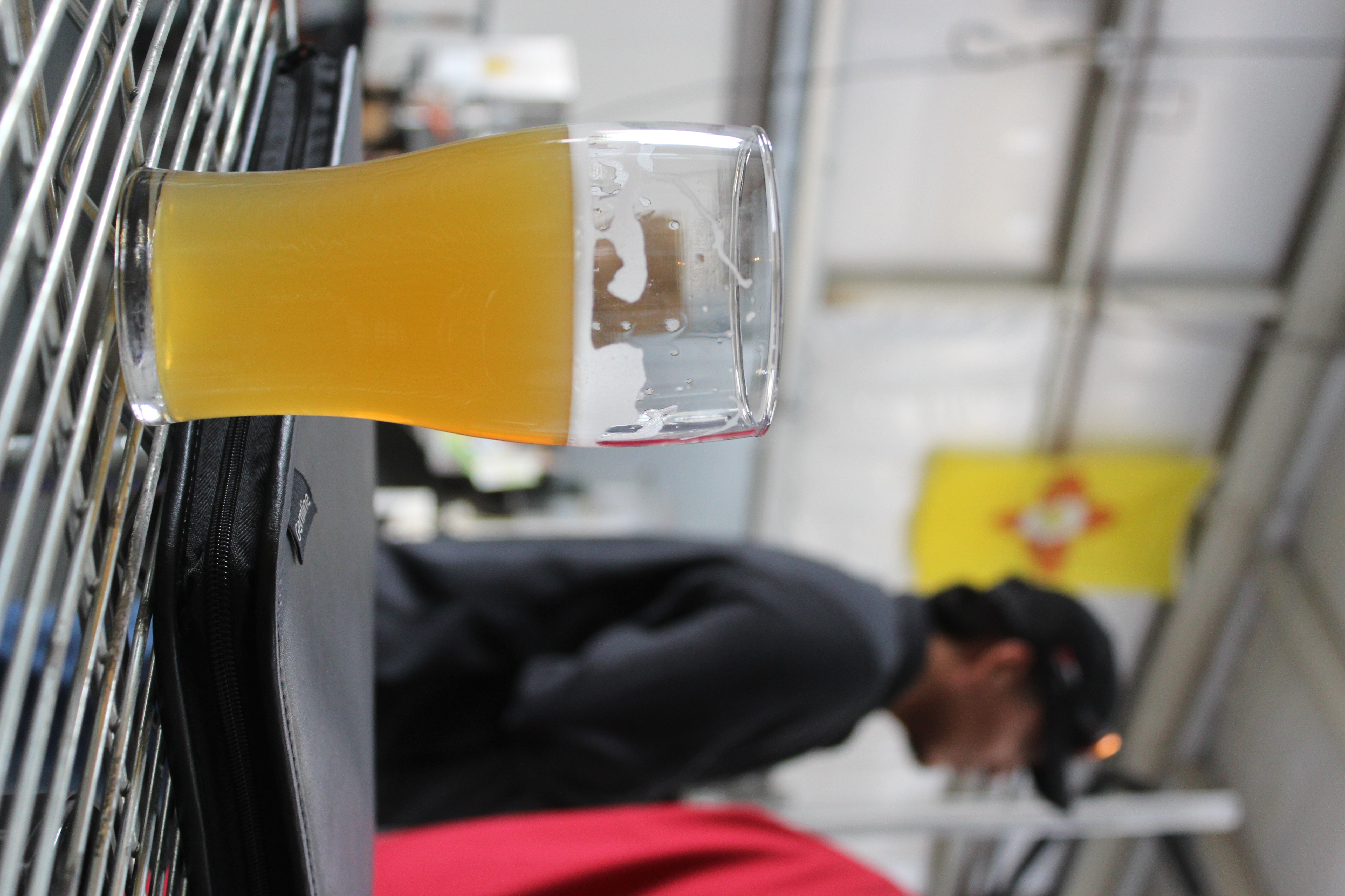 A pint in focus, brewhouse and Zia flag in the soft background